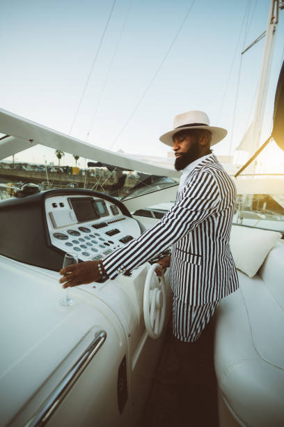 um homem negro está dirigindo um barco de luxo. - speed boat versus sail boat - fotografias e filmes do acervo