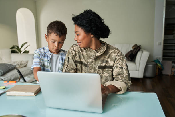 Black mother and son using laptop at table stock photo