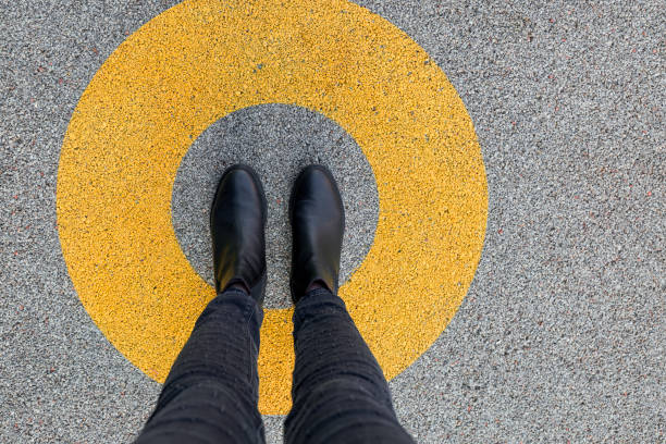black shoes standing in yellow circle on the asphalt concrete floor. comfort zone or frame concept. feet standing inside comfort zone circle - trilhos pedestres imagens e fotografias de stock