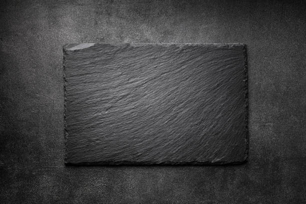 Black slate board on dark stone texture top view. Empty space for menu or recipe. Black slate board on dark stone table texture top view. Empty space for menu or recipe. slate rock stock pictures, royalty-free photos & images