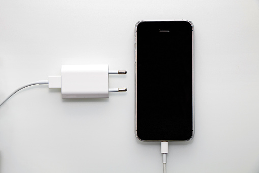 Black smartphone, adapter and cable on a white background