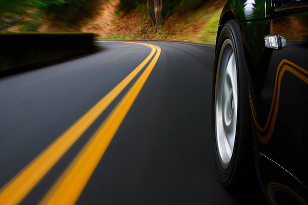 A black sports car driving around a curve stock photo