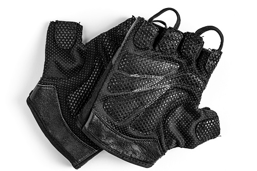 Small black sports gloves for athletic exercises and pull-ups on the horizontal bar. They lie in the center of a white background (isolate) with the inside up. Open gloves (fingerless).