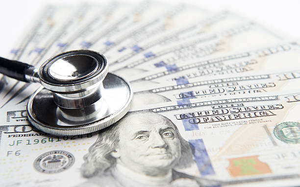 Black stethoscope laying on top of money stock photo