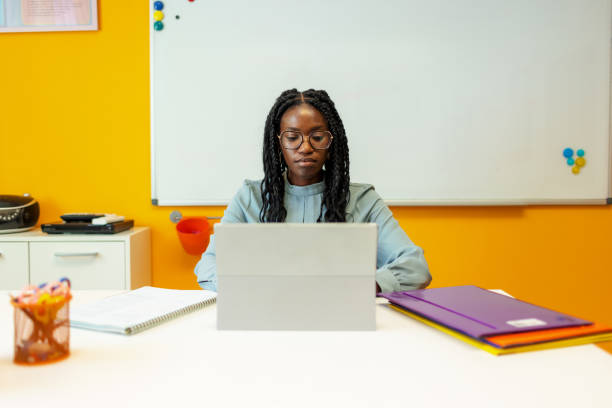 Black Teacher Sitting At Her Desk In The Classroom stock photo