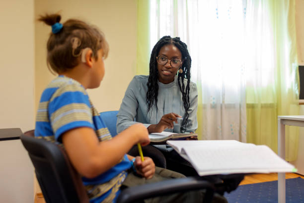 Black Teacher Works With Student In The Classroom stock photo