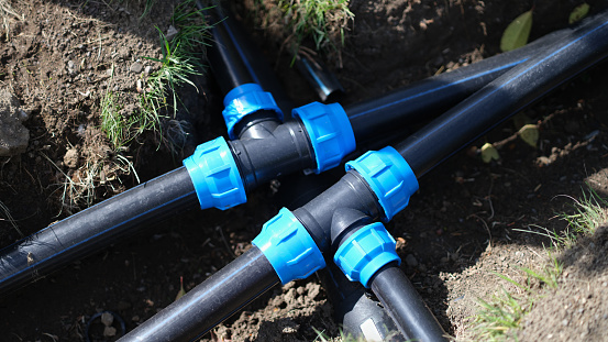Black three way plastic water pipe on grass. Irrigation system in the garden concept