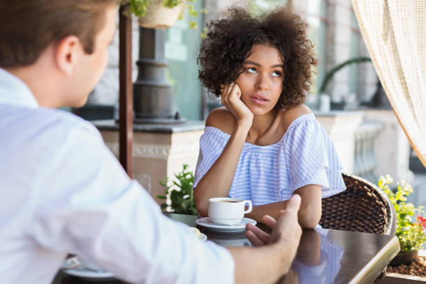Black woman disinterested with blind date outdoors Black woman disinterested with blind date at outdoor cafe boredom stock pictures, royalty-free photos & images