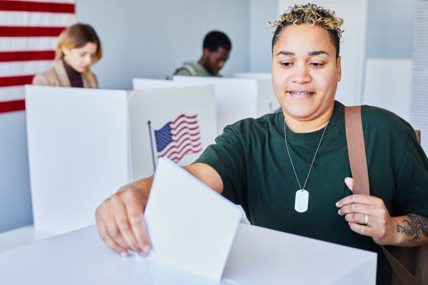 Black Woman Putting Voting Ballot in Bin stock photo