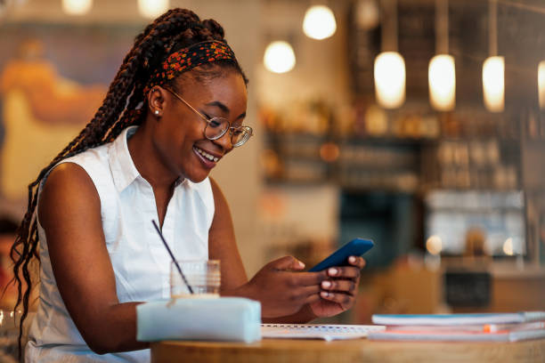 Black woman using cellphone at cafe stock photo