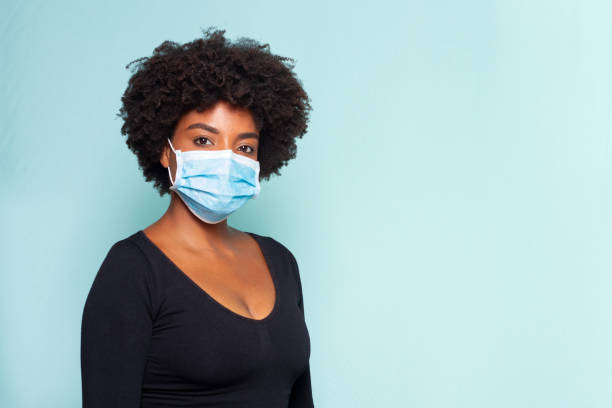 black woman wearing protection mask young woman wearing protection mask against covid-19 with blue background puerto rican women stock pictures, royalty-free photos & images