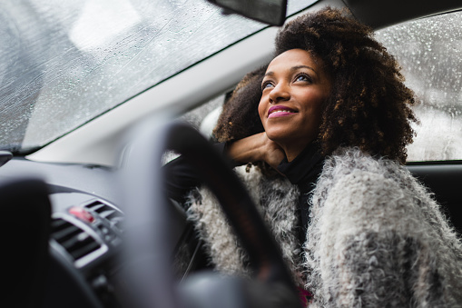 Black young woman inside a car in winter while its raining