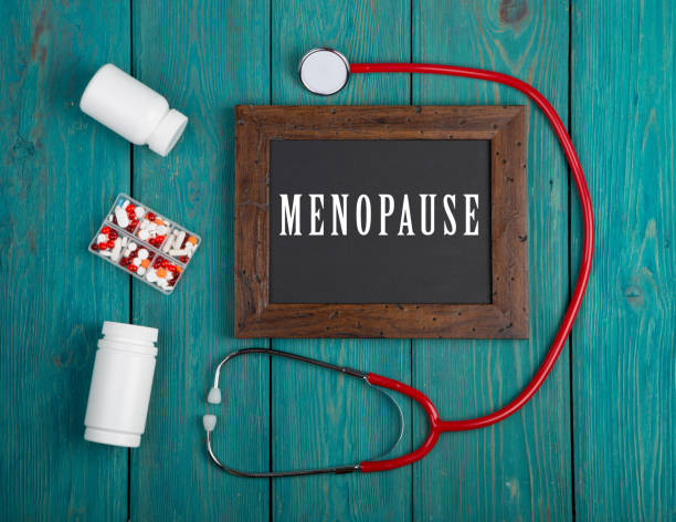 Blackboard with text "Menopause", stethoscope, pills on blue wooden background stock photo