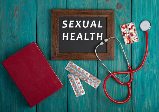 Blackboard with text "Sexual Health", book, pills and stethoscope on blue wooden background stock photo
