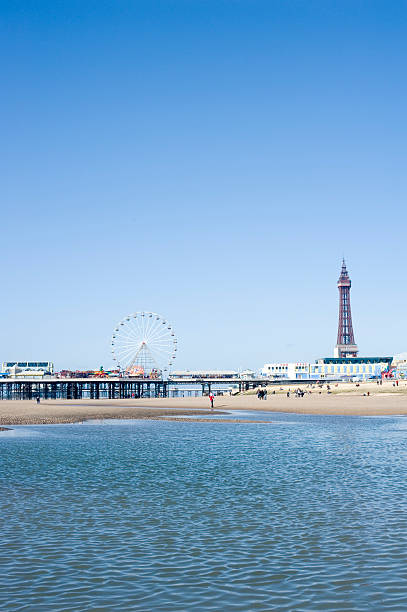 Blackpool Tower and piers, Blackpool, England View across the sea of the waterfront and beach with the Blackpool Tower and piers, Blackpool, England blackpool tower stock pictures, royalty-free photos & images