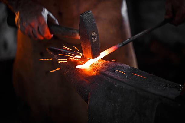 Blacksmith manually forging the molten metal The blacksmith manually forging the molten metal on the anvil in smithy with spark fireworks blacksmith stock pictures, royalty-free photos & images