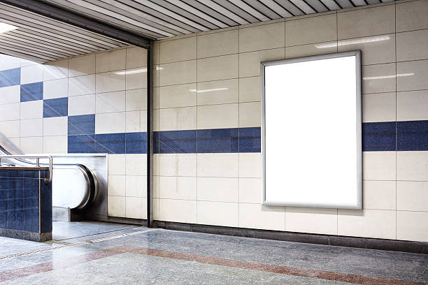 Blank billboard in a subway station wall. Blank billboard in a subway station wall. Wall is made of tiles and there is a blue coloured border in the middle. Billboard is oriented vertically and standing on the right side of frame. Billboard is empty so you can write or add something on it. - Clipping path of billboard included. billboard posting stock pictures, royalty-free photos & images
