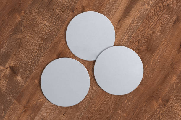 Blank coasters Three round white coasters on wood background. 3d illustration coaster stock pictures, royalty-free photos & images