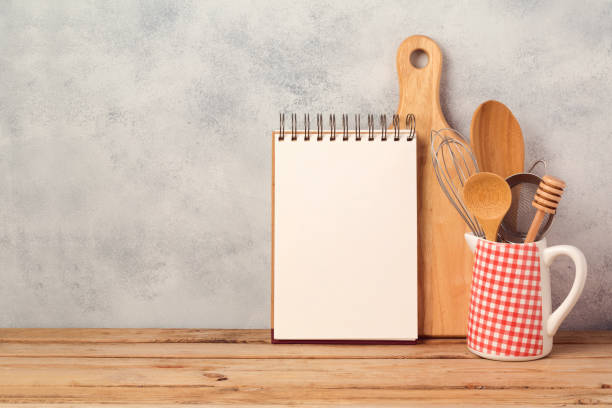 Blank notebook and kitchen utensils on wooden table over rustic background with copy space Blank notebook and kitchen utensils on wooden table over rustic background with copy space recipe stock pictures, royalty-free photos & images