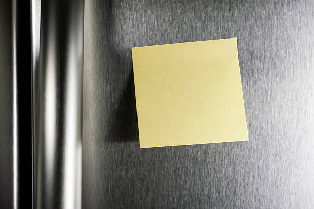 A blank post it note on a stainless steel refrigerator door stock photo