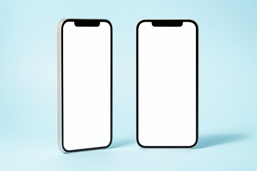 Blank screen mockup, template on blue background. Two phones standing on blue background. Front view and three-quarter front view.