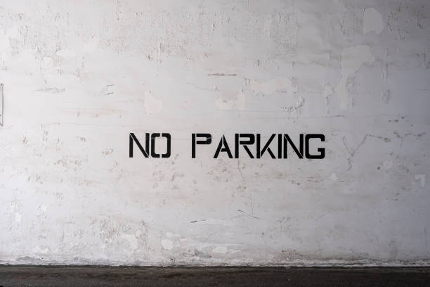 Blank Stencilled Painted No Parking Sign On White Weathered Wall With Pealing Paint stock photo