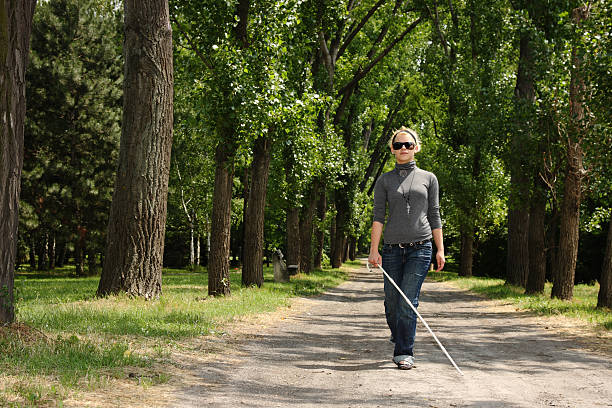ciego mujer caminando en un parque - ceguera fotografías e imágenes de stock