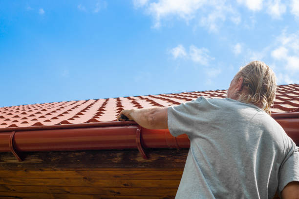 Blockage in the drainpipe. A man removes trash from a roof chute stock photo
