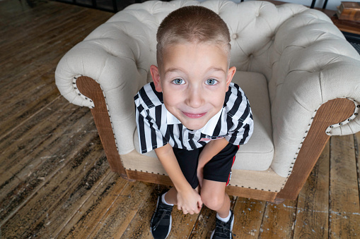 blond gray-eyed boy in striped shirt smiles beautifully