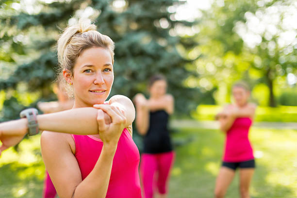 blond girl streching her arms Cheerful young woman streching her arm before jogging individual event stock pictures, royalty-free photos & images