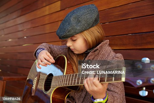 istock blond kid girl playing guitar with winter beret 1344916426