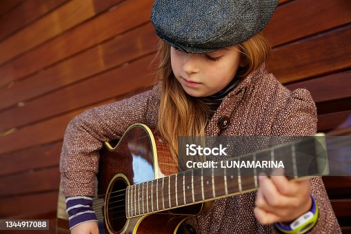 istock blond kid girl playing guitar with winter beret 1344917088