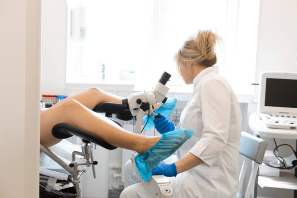 eine blonde ärztin, gynäkologin untersucht einen patienten, der in einem gynäkologischen stuhl sitzt. untersuchung durch einen gynäkologen. gesundheitskonzept für frauen - kolposkopie stock-fotos und bilder
