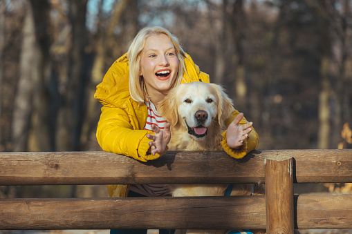 A blond woman hugging her retriever dog in the park. Pet care concept. Beautiful woman enjoys spending time with her dog outdoor. Happiness and friendship. Pet and woman.