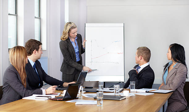 Blonde female present graph on flipchart during business meeting,...
