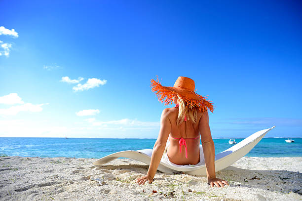 Blonde woman with orange hat on Mauritius beach stock photo