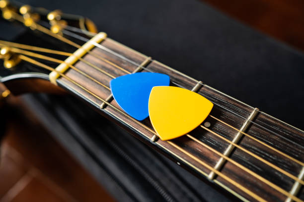 Blue and yellow guitar picks on an acoustic guitar stock photo