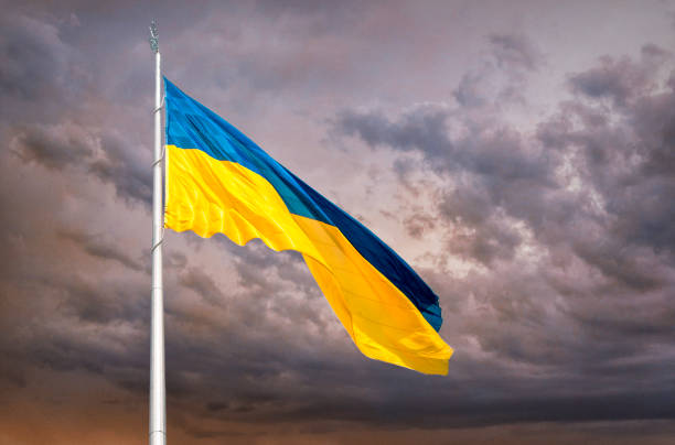 Blue and yellow national flag of Ukraine waving in the wind against the backdrop of the sunset sky majestic high banner and the state blue-and-yellow flag of ukraine, waving against the background of a purple sunset stormy sky. Celebration of the Independence Day of Ukraine, August 24. The concept of danger, armed conflict in Ukraine, patriotism and courage military invasion stock pictures, royalty-free photos & images