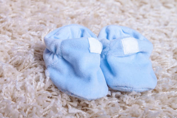 Blue Baby's bootees on the white carpet. stock photo