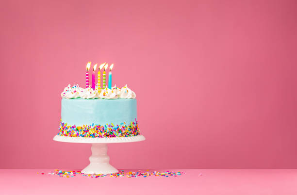 Blue Birthday Cake with Five Candles over Pink Background stock photo