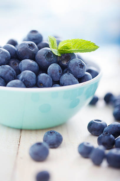 A blue bowl overfilled with blueberries stock photo