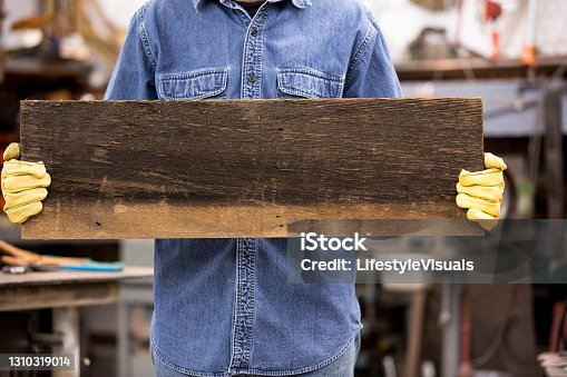 istock Blue Collar worker wearing work gloves holds blank sign ready for you own copy/text. 1310319014