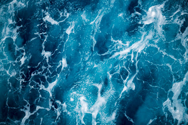 Blue deep sea foaming water background Close-up of foaming water from the back of a ship foam material stock pictures, royalty-free photos & images