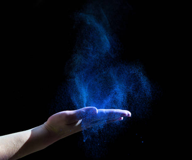 Blue holi paint explosion through woman hand on black Blue holi paint explosion through woman hand on black background, copy space holi photos stock pictures, royalty-free photos & images