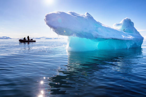 Blue ice iceberg in Nordfjorden, Svalbard, with the sun shining through stock photo