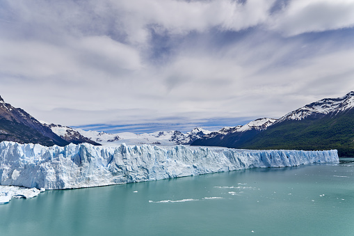 Blue ice of Perito Moreno Glacier in Glaciers national park in Patagonia, Argentina with turquoise water of Lago Argentino in the foreground, dark green forests and sow covered mountains of the Andes in the distance_2