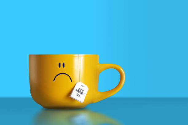 niebieska herbata poniedziałek. duży smutny żółty kubek. - blue monday zdjęcia i obrazy z banku zdjęć