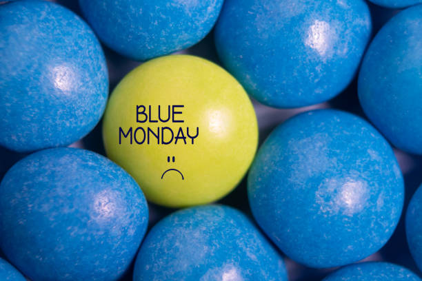 синий понедельник текст. конфеты желтые в синем. - blue monday стоковые фото и изображения