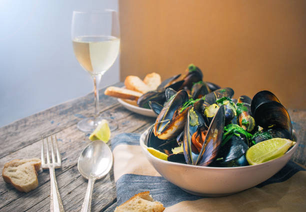 Blue mussles with vine and baguette on wooden table stock photo