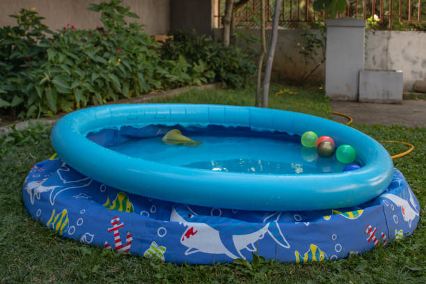 blue plastic children's pool filled with water in the garden on the grass - zwembad vullen achtertuin stockfoto's en -beelden